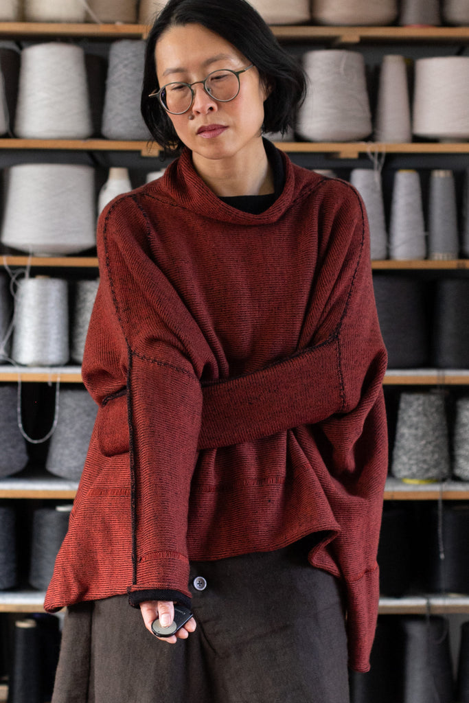 Front view of box shaped jumper designed by Wendy Voon, in vermilion with black backed fabric, made from superfine merino wool.