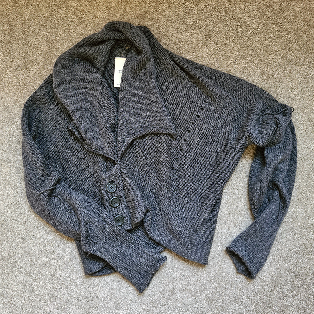 Charcoal knitted cardigan with buttons on a beige carpet