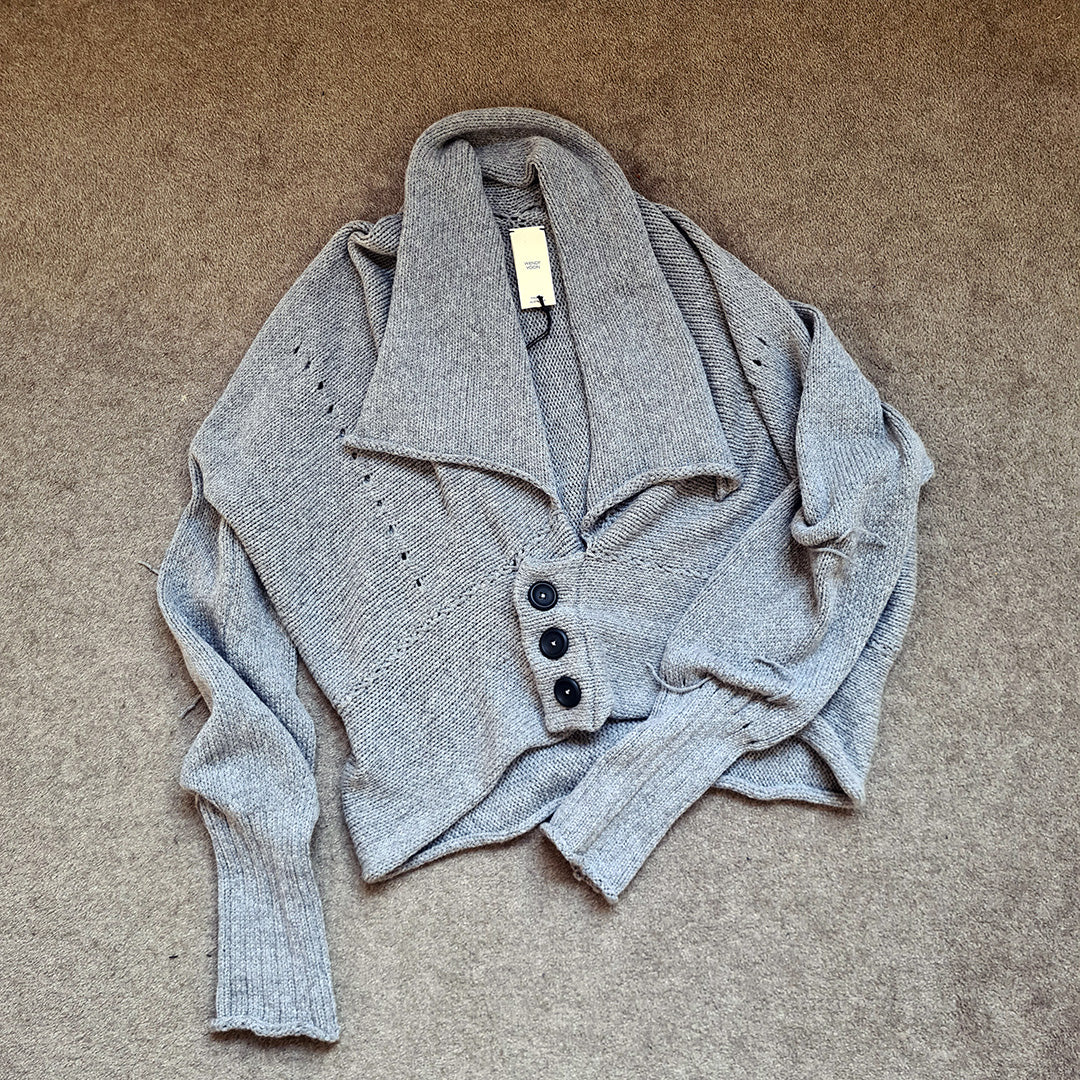 Soft grey knitted cardigan with buttons on a beige carpet