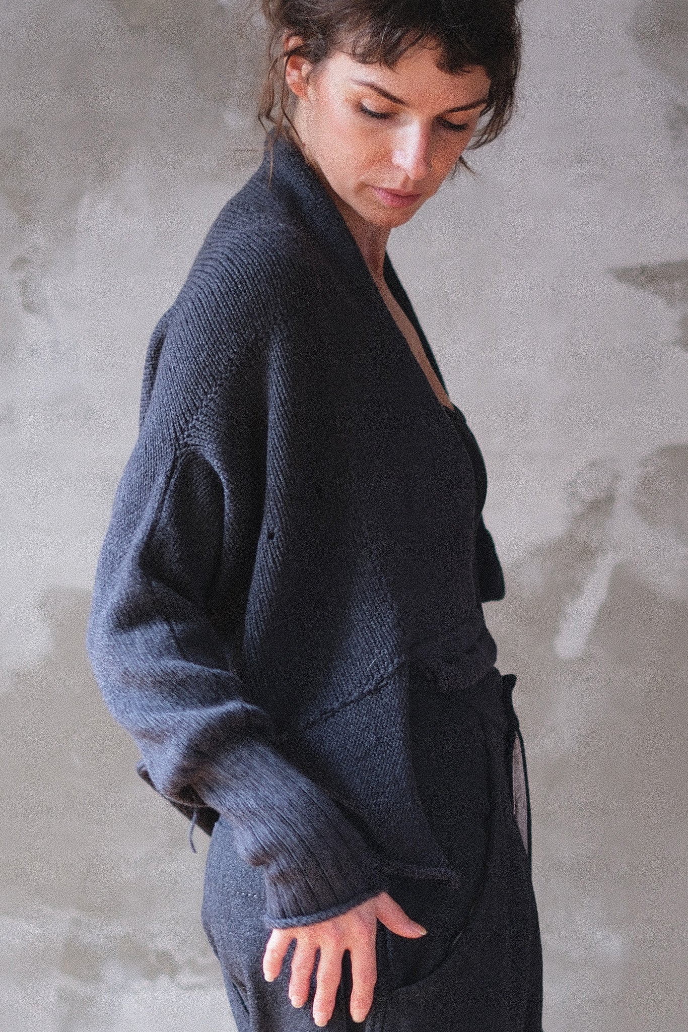 Side view of model wearing a charcoal chunky knit cardi upside down.