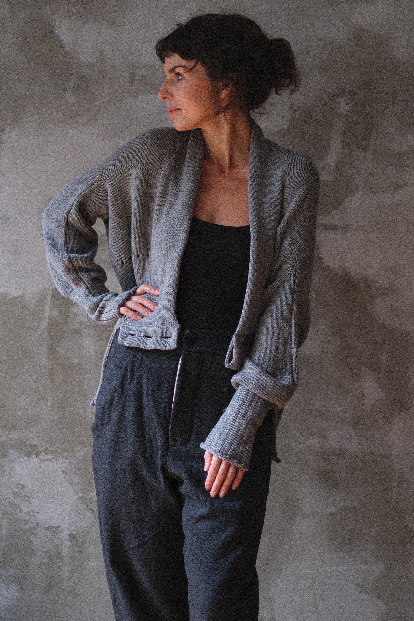 Model wears soft grey chunky knit cardi upside down.