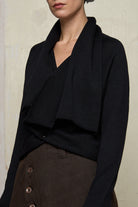 Model wears a knitted shawl collared cardigan upside down and pinned at the waist in a black colourway.  Cardigan is designed and knitted in  Melbourne by Wendy Voon knits.
