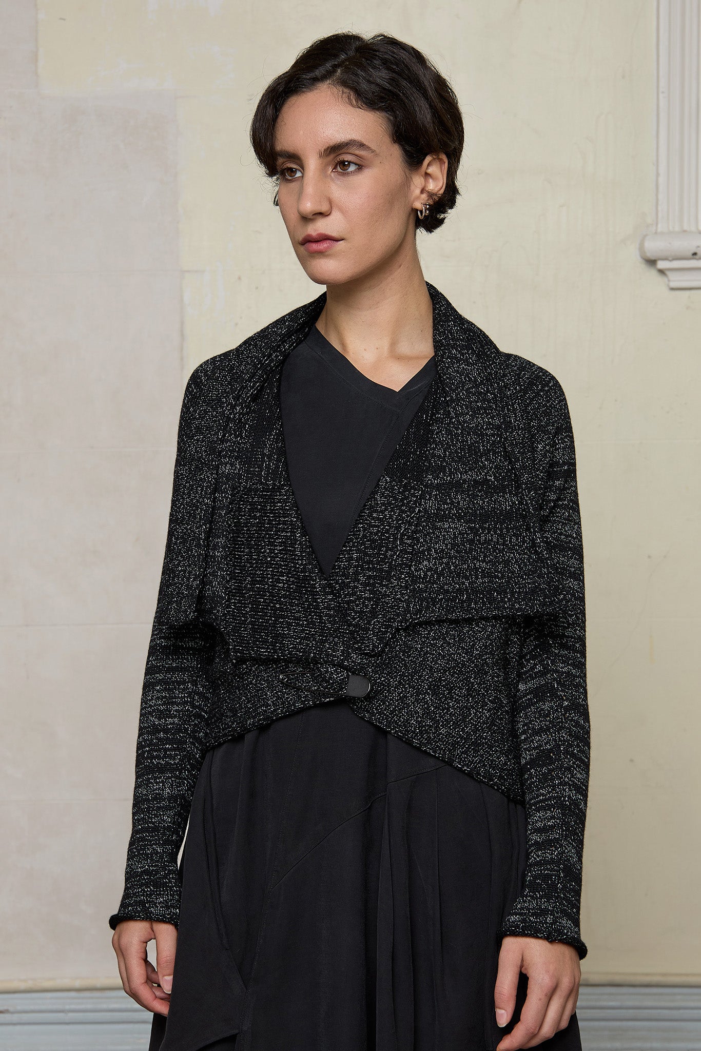 Model wears a black with white flecks shawl collared cardigan upside down, and is cinched at the waist with a safety pin.