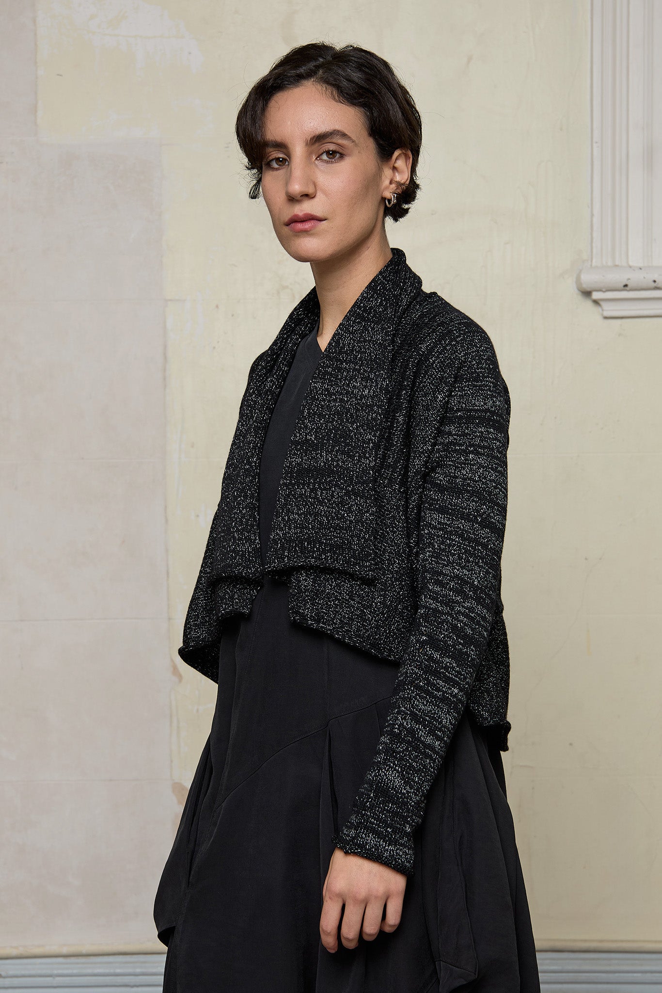 Model wears a black with white flecks shawl collared cardigan upside down.