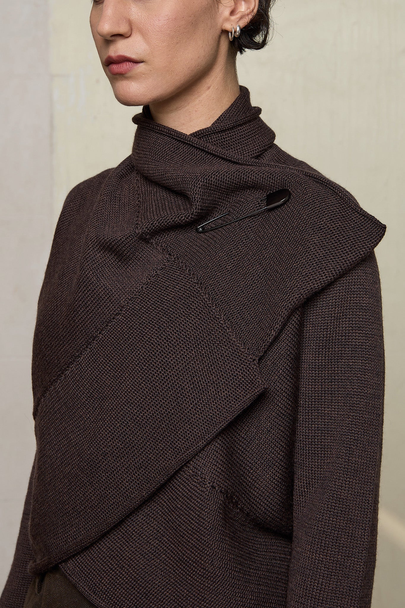 Model wears a knitted shawl collared cardigan upside down and pinned at the neck in a chocolate brown colourway.  Cardigan is designed and knitted in  Melbourne by Wendy Voon knits.