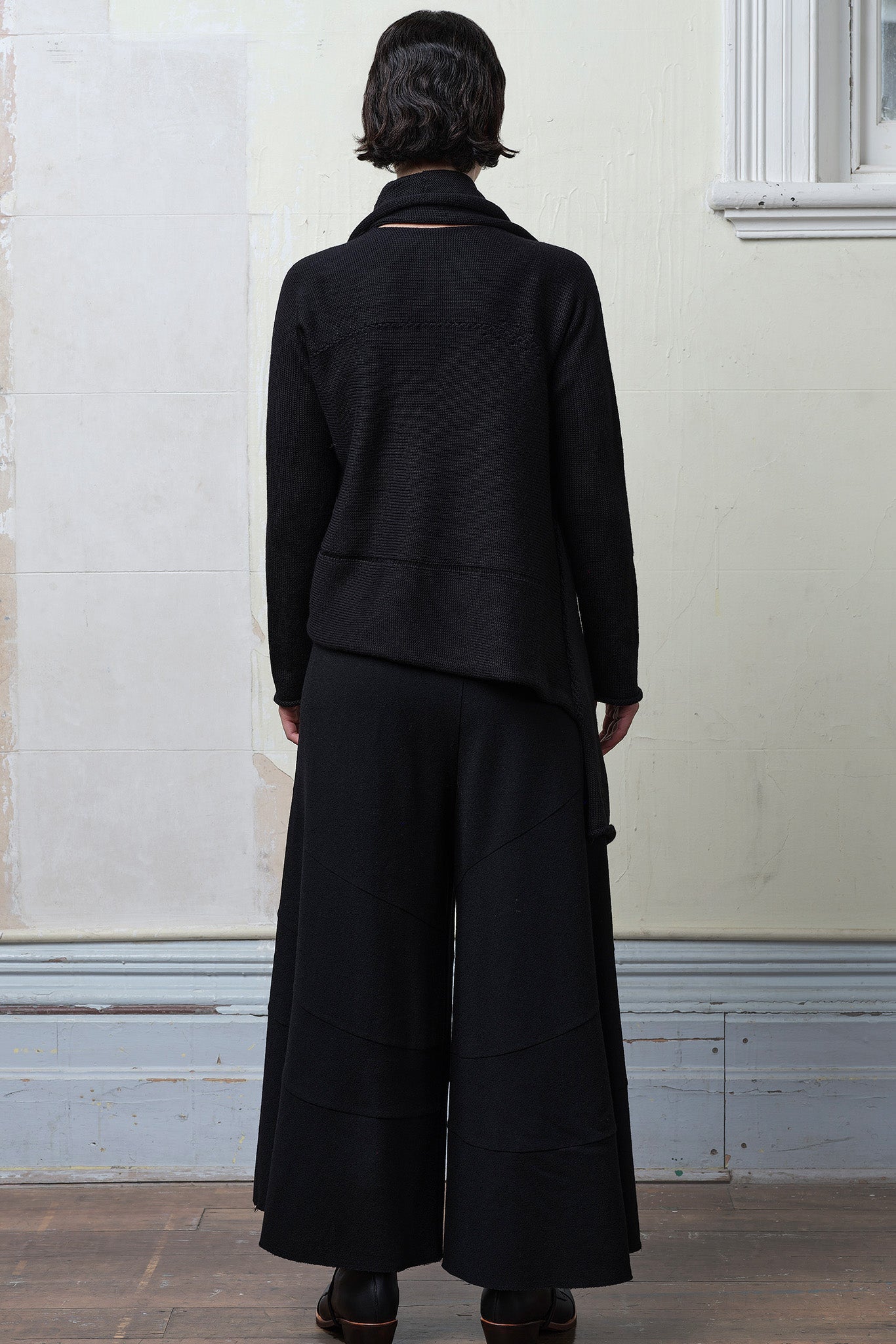 Model wears knitted merino cross over, slung behind, in black colourway.