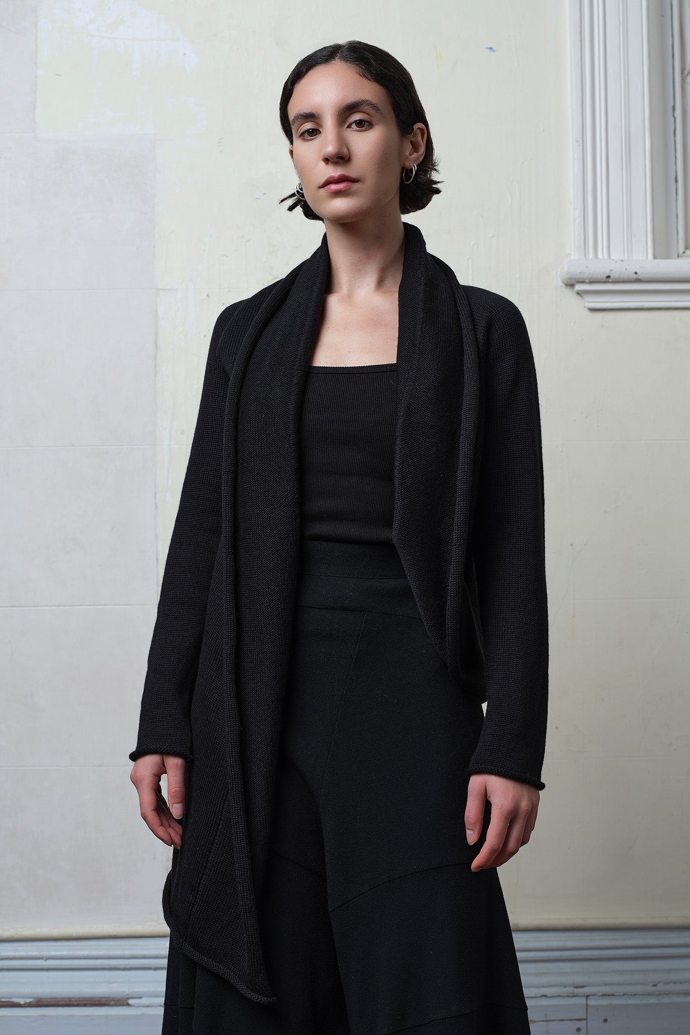 Model wears knitted merino cross over, slung behind, in black colourway.