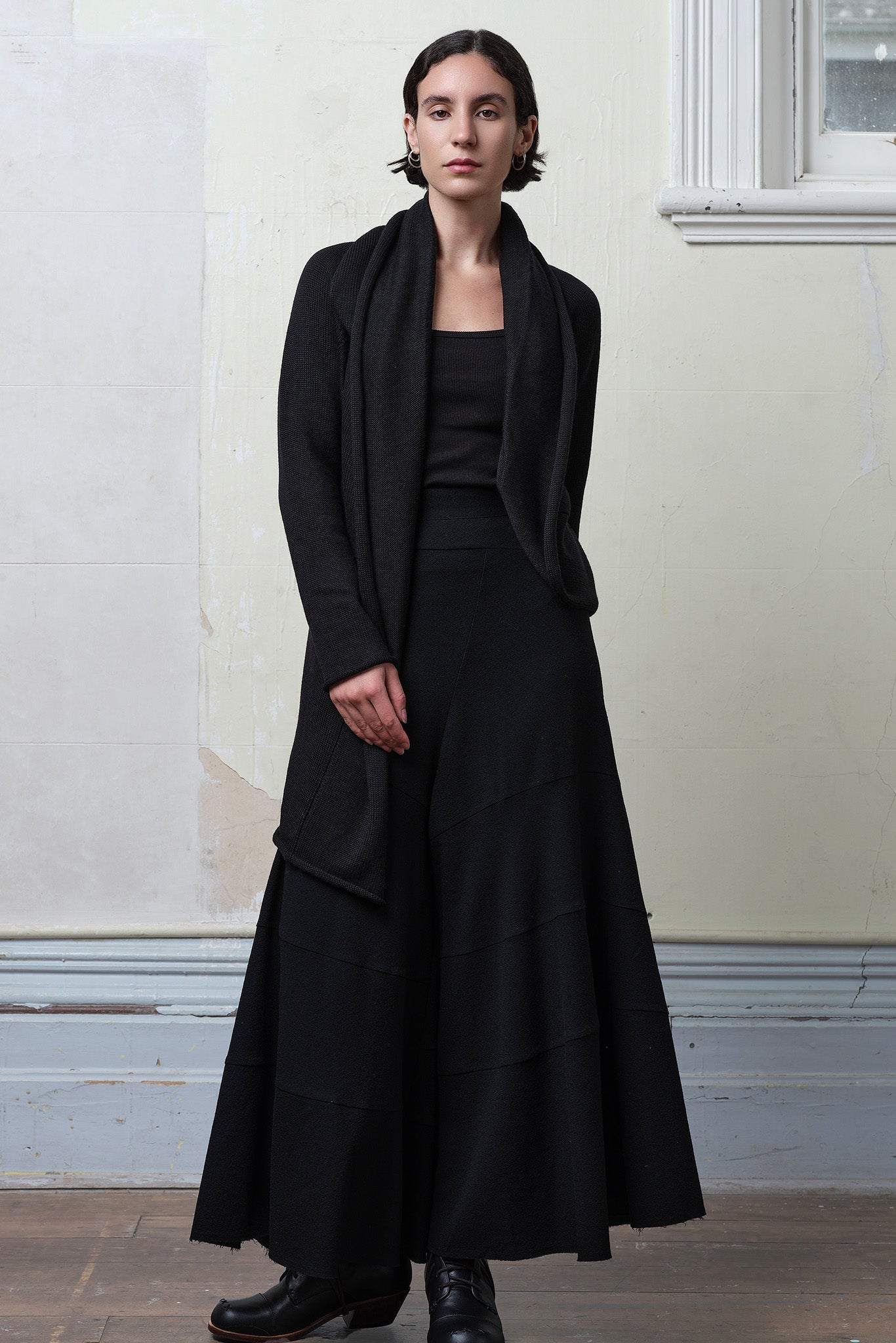 Model wears knitted merino cross over, slung behind, in black colourway.