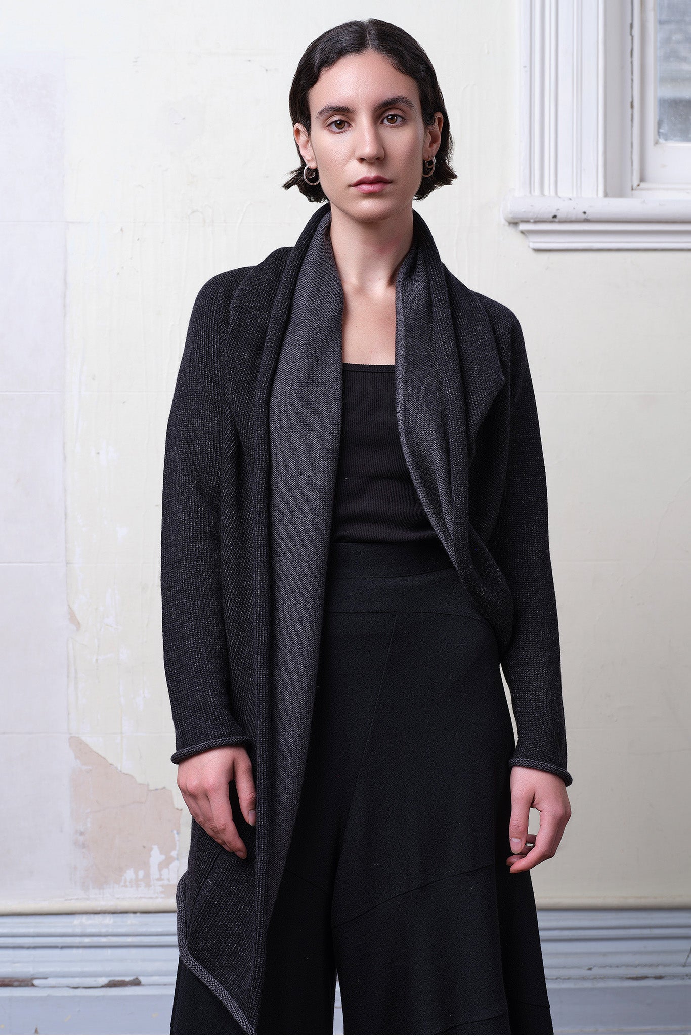 Model wears knitted merino cross over, slung behind, in black and charcoal colourway.