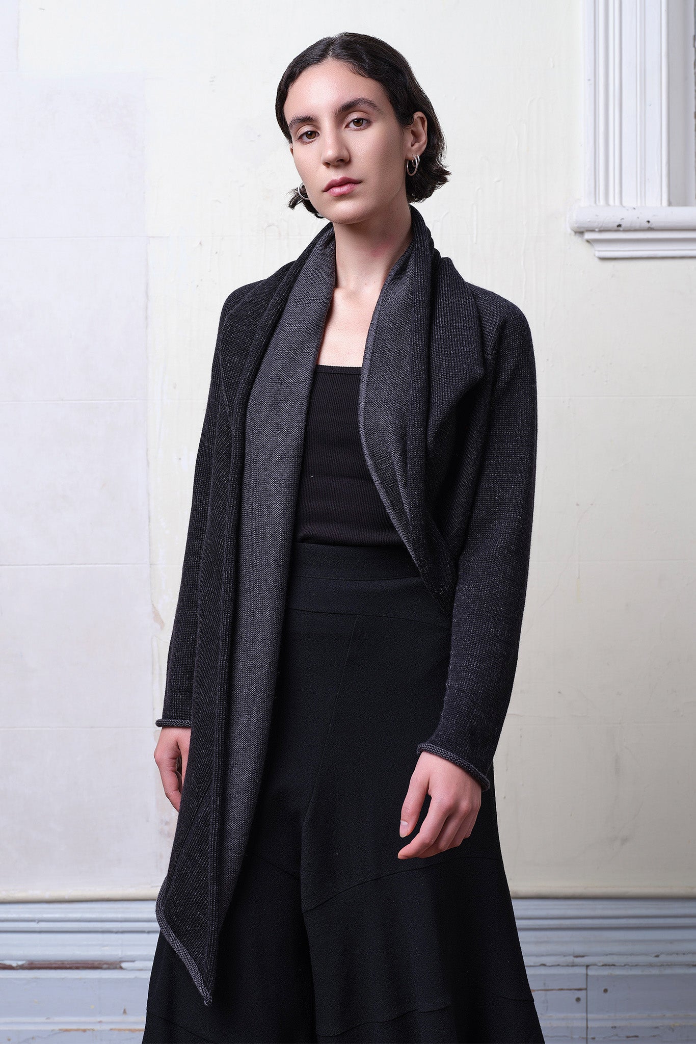 Model wears knitted merino cross over, slung behind, in black and charcoal colourway.
