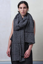 Model wears knitted alpaca wrap in storm grey with contrasting slate cotton stripes.