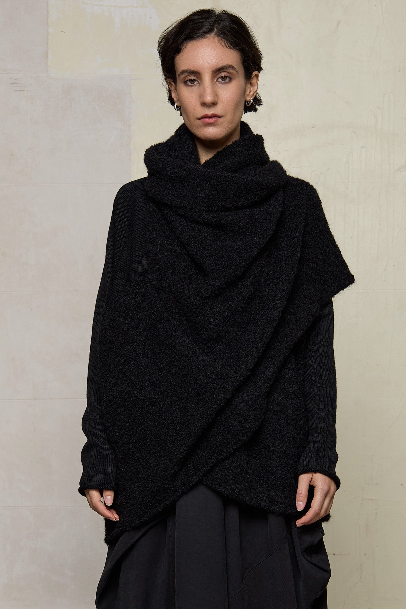 Model wears black knitted coat upside down, made from alpaca and superfine merino wool.