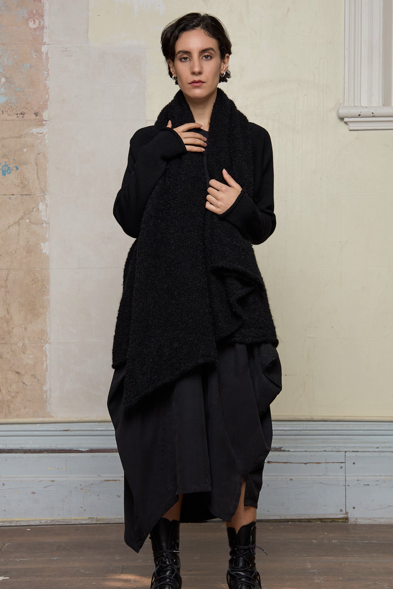Model wears black knitted coat upside down, made from alpaca and superfine merino wool.