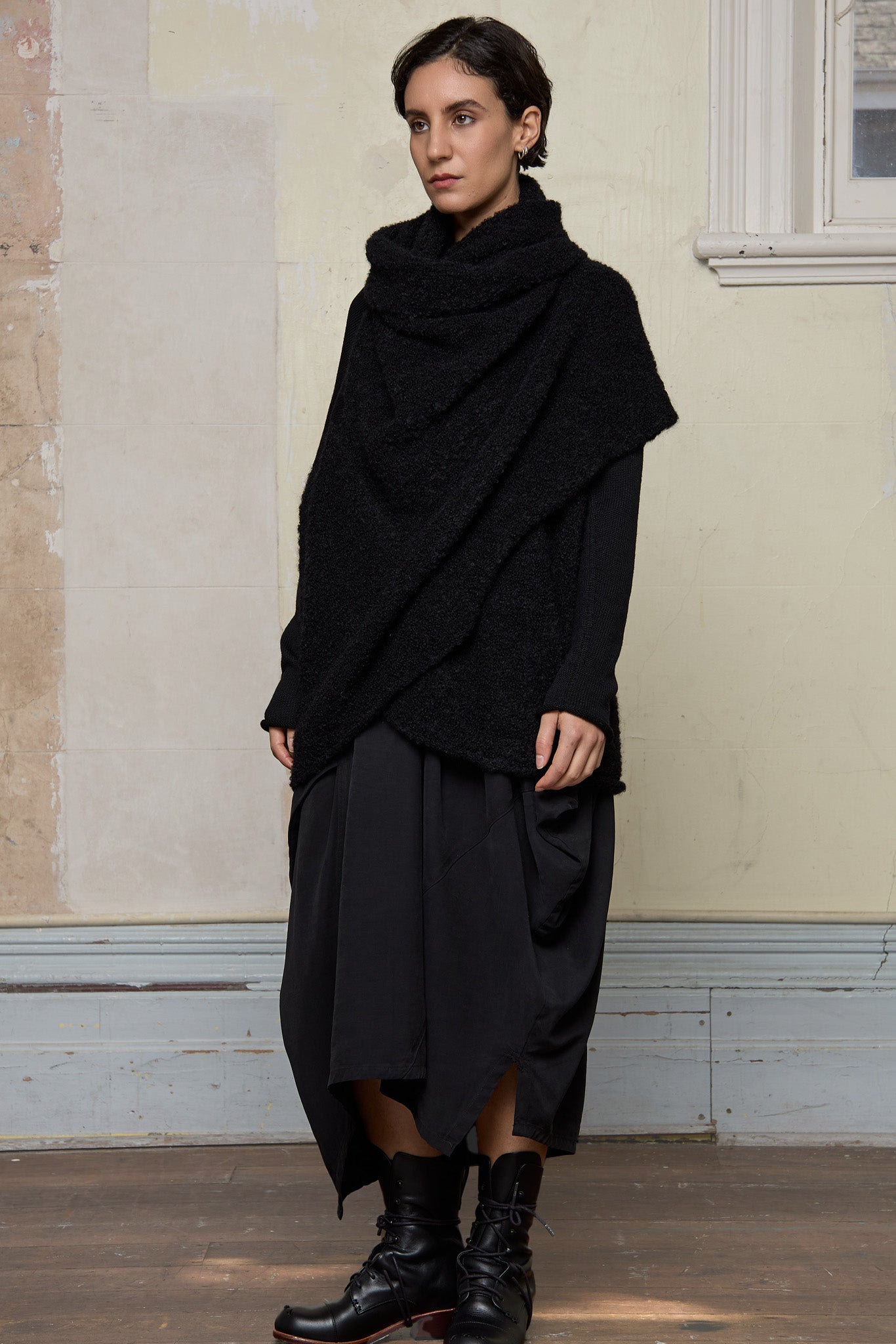 Model wears black knitted coat upside down, made from alpaca and superfine merino wool.