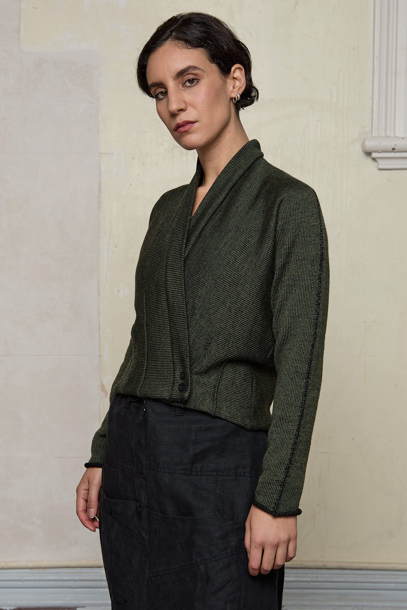 Model wears welted wool cardigan buttoned up in army backed with black colourway. Designed and made in Melbourne by Wendy Voon knits.