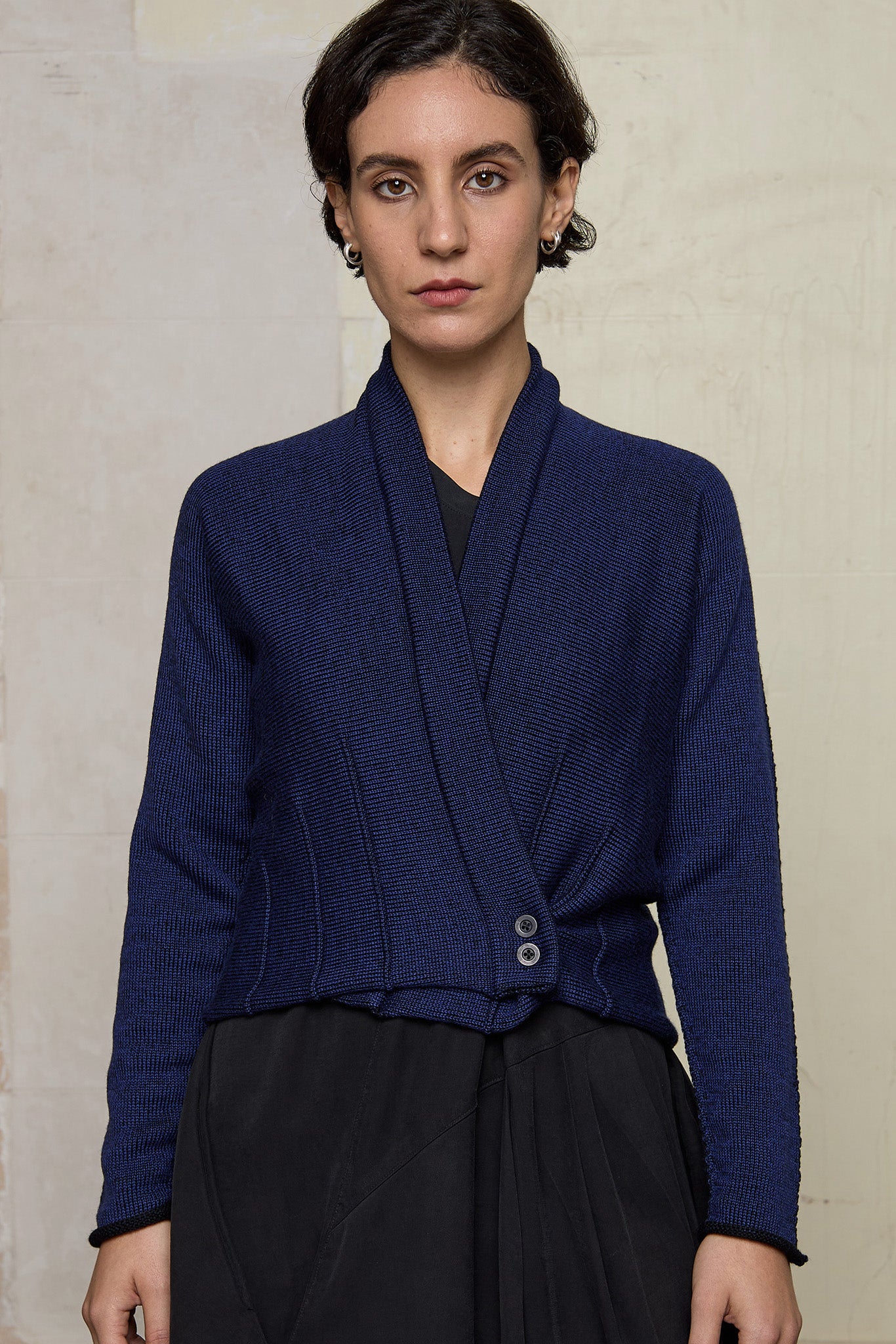 Model wears welted wool cardigan buttoned up in blue backed with black colourway. Designed and made in Melbourne by Wendy Voon knits.