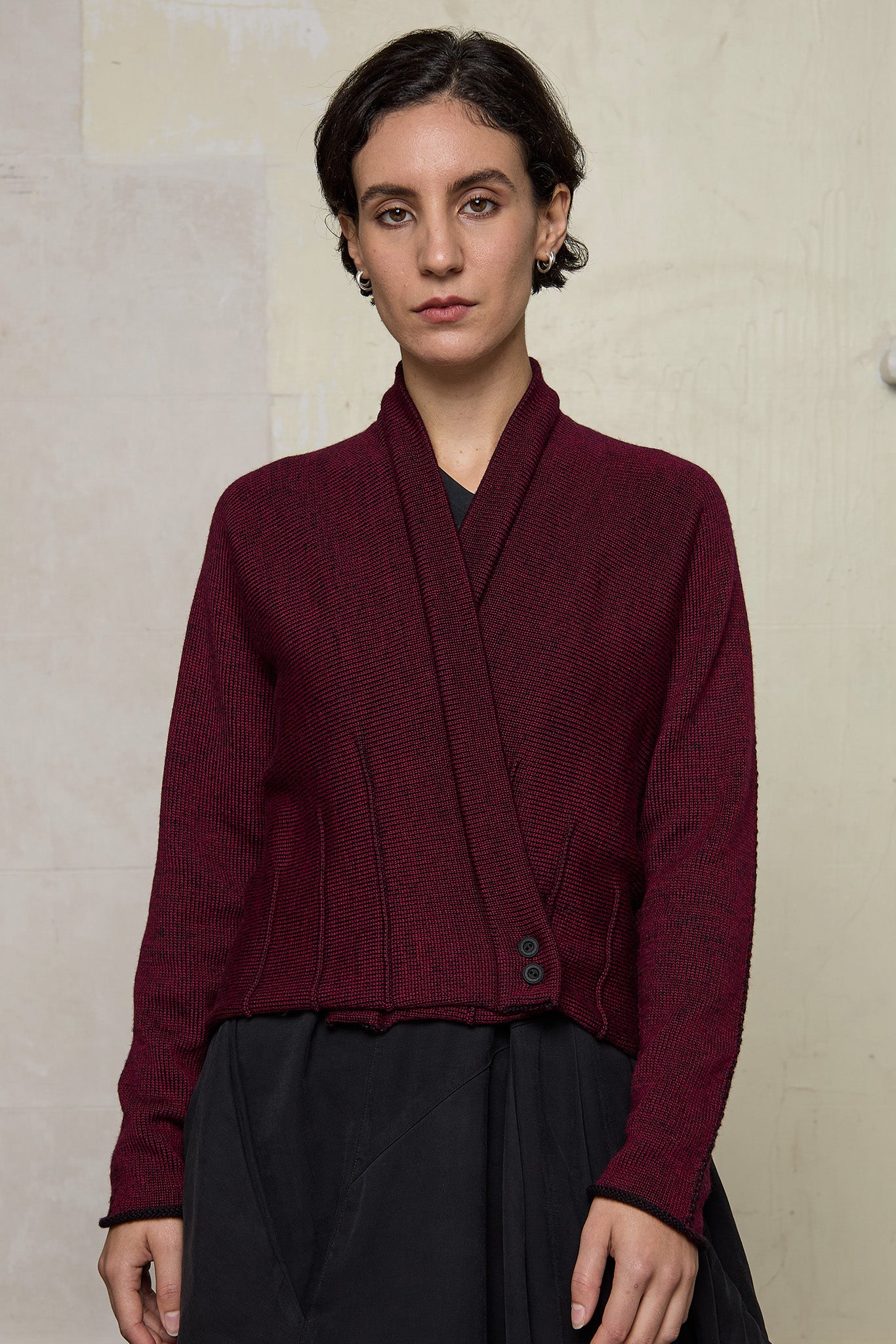 Model wears welted wool cardigan buttoned up in burgundy backed with black colourway. Designed and made in Melbourne by Wendy Voon knits.