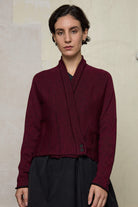Model wears welted wool cardigan buttoned up in burgundy backed with black colourway. Designed and made in Melbourne by Wendy Voon knits.