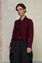 Model wears welted wool cardigan buttoned up in burgundy backed with black colourway. Designed and made in Melbourne by Wendy Voon knits.