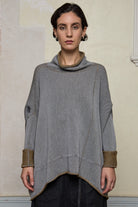 Front view of boxed jumper worn inside out, grey/blue is outside and mustard is inside.