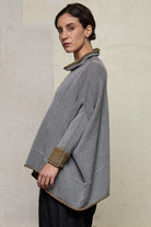 Side view of model wearing a wool boxed shaped jumper in mustard backed with grey merino wool, worn inside out. Designed and made in Melbourne by Wendy Voon knits.