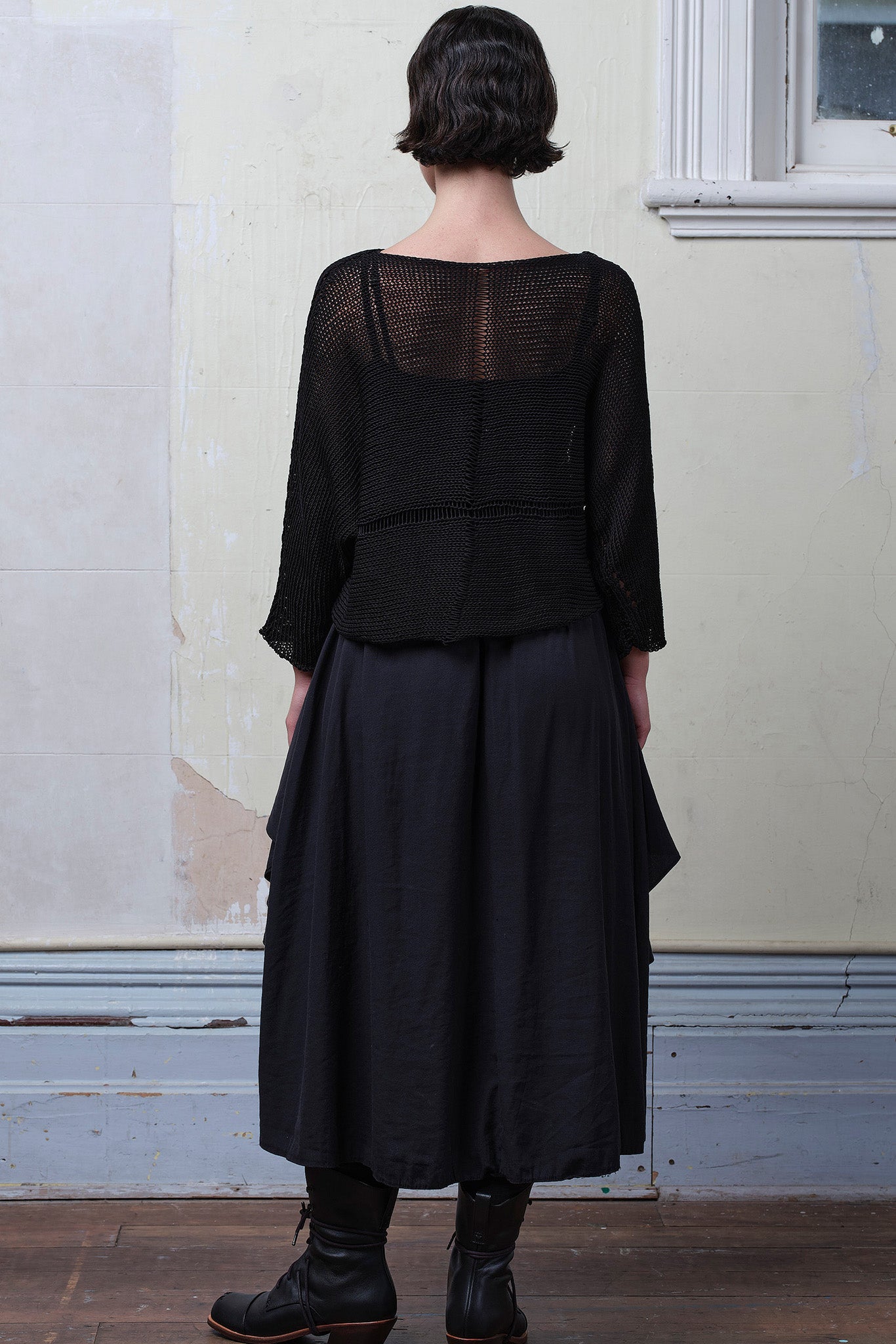 Back view of model wearing Cotton Batwing  in black colourway, featuring lace details along garment seam,  designed by Wendy Voon knits.