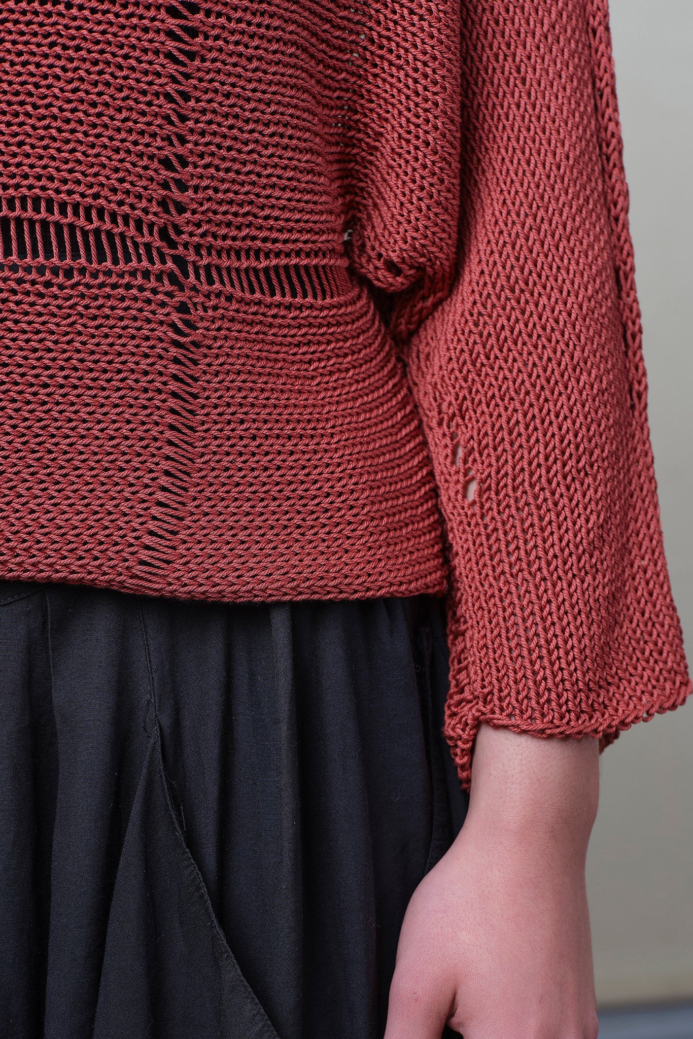 Close up fabric detail of Cotton Batwing  in coral colourway, featuring large stitch details,  designed by Wendy Voon knits.