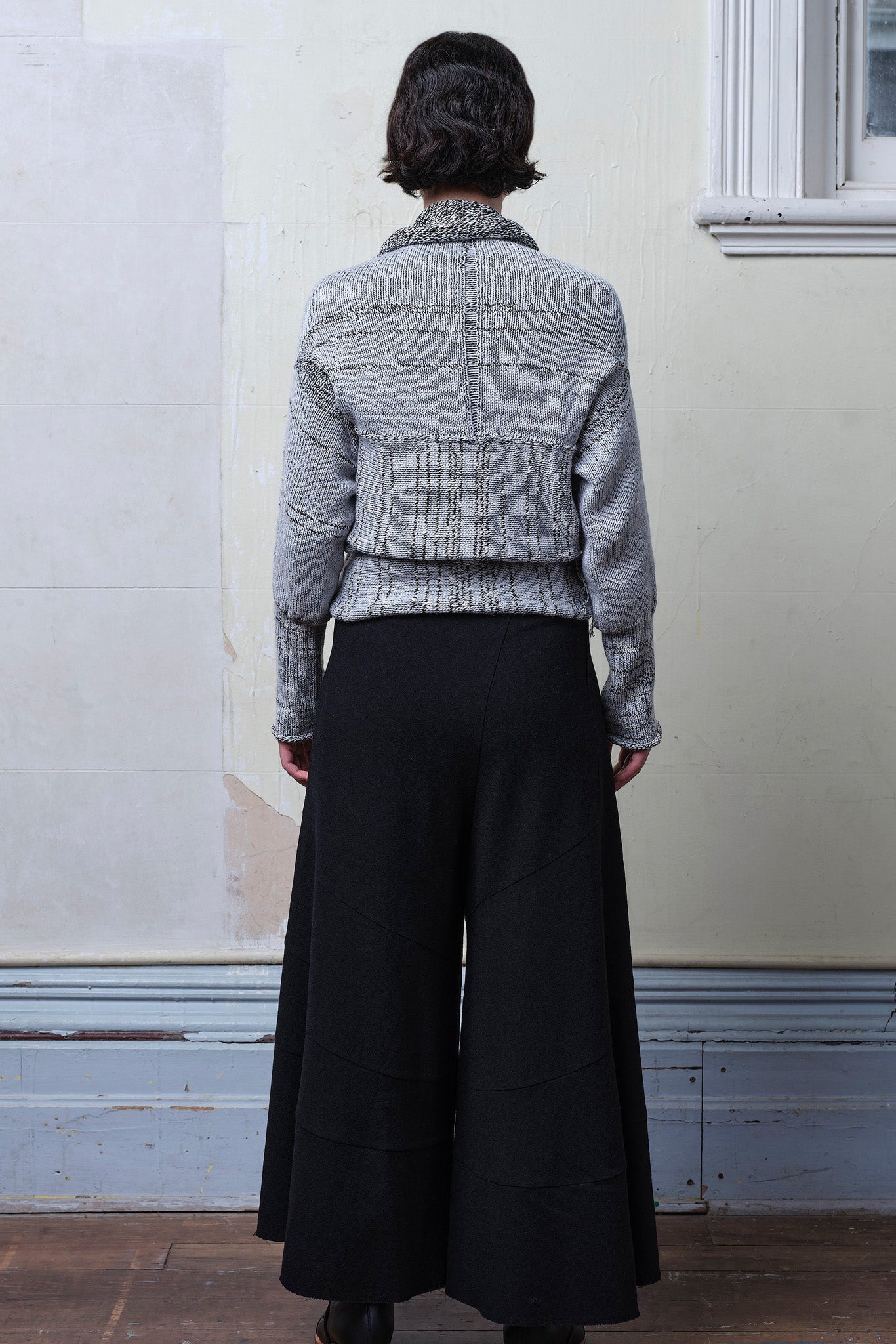 Model wears cotton and superfine merino ruched cardigan upside down in white, grey and black melange colourway.