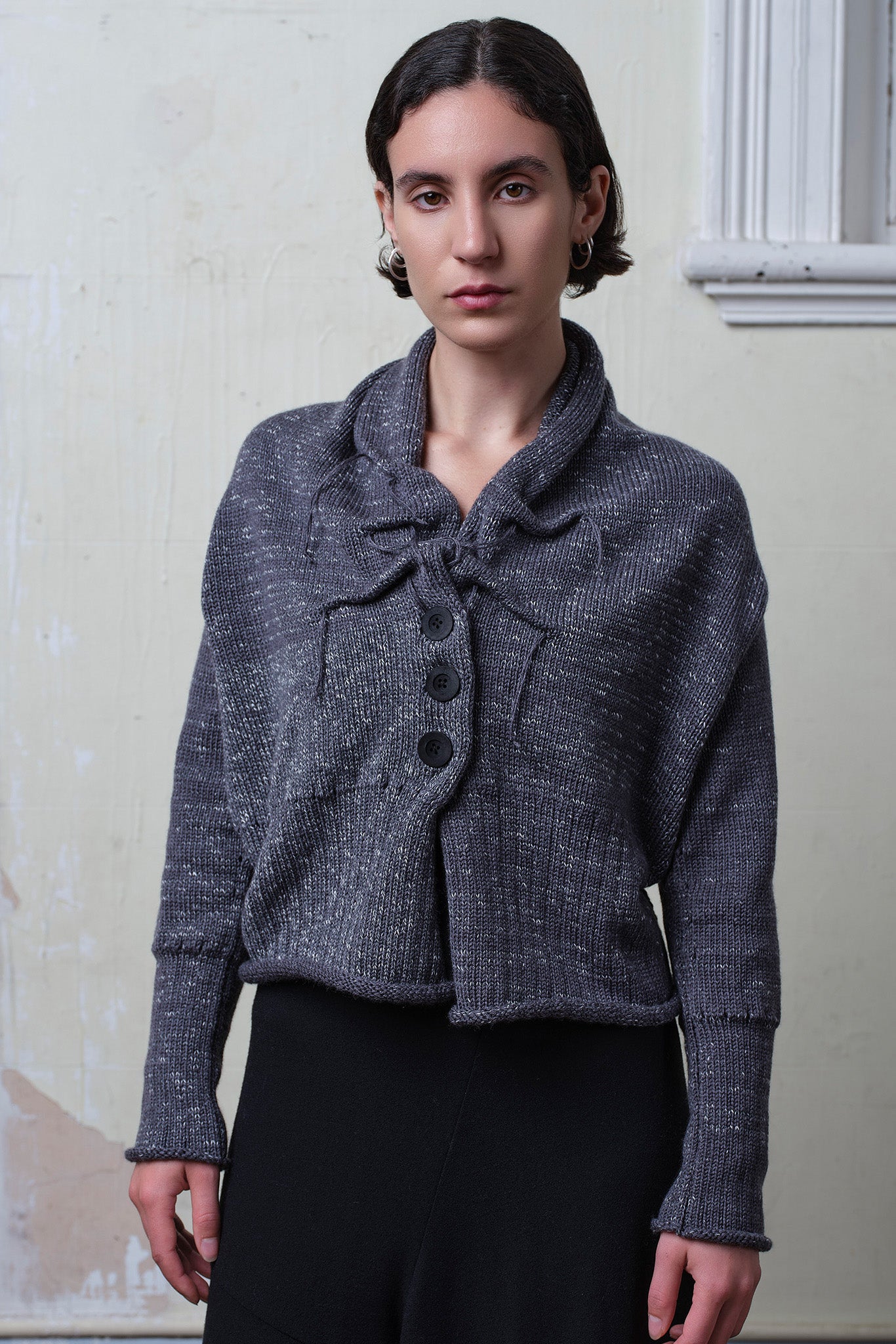 Front view of model wearing a chunky knit wool ruched cardigan in a grey with white flecked colourway.