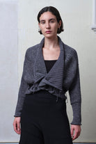 Front view of model wearing a chunky knit wool ruched cardigan upside down, in a grey with white flecked colourway.