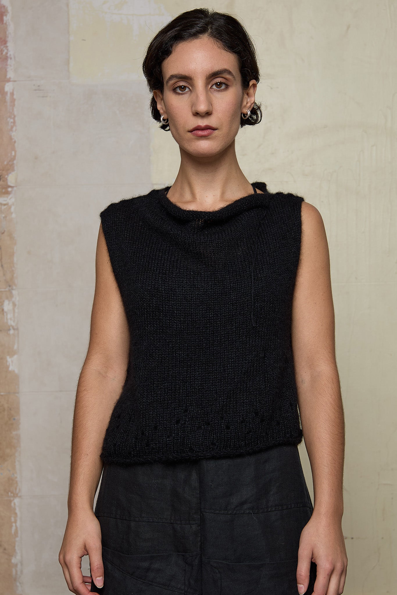 Model wears super lush knitted vest in black. Vest features random laceholes along hemline.