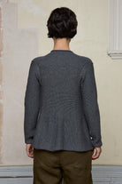 Back view of model wearing knitted peplum riding coat in steel grey, featuring vintage cloth covered buttons.  Made from superfine merino.
