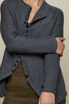 Close up fabric view knitted peplum riding coat in steel grey, featuring vintage cloth covered buttons.  Made from superfine merino.