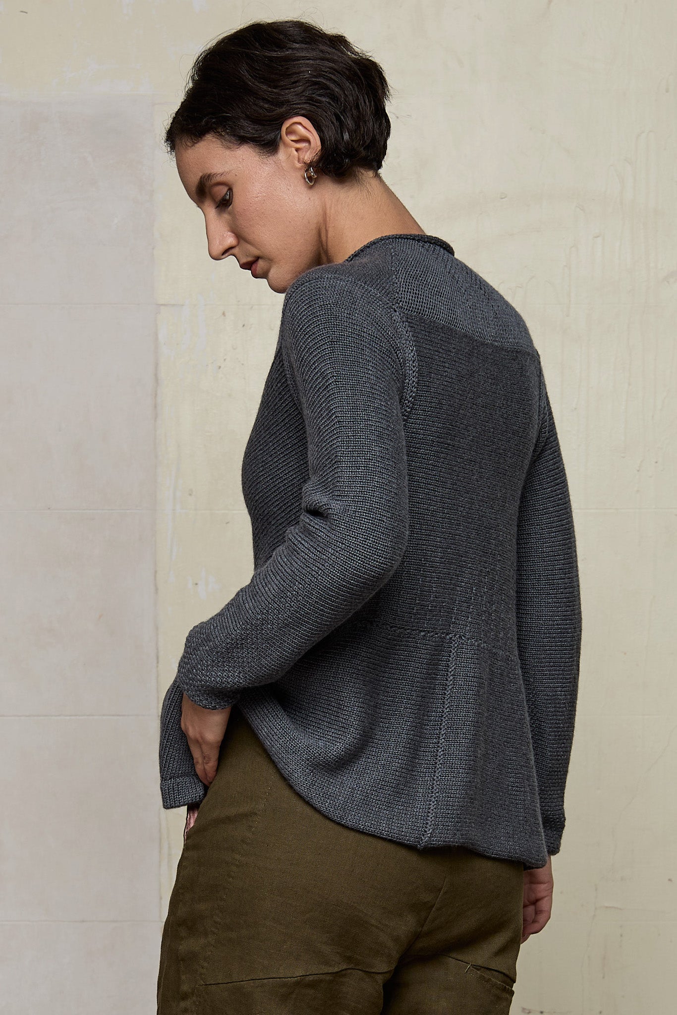 Model wears knitted peplum riding coat in steel grey, featuring vintage cloth covered buttons.  Made from superfine merino.