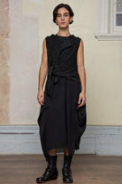 Model wears asymmetric self-curling vest in silver metallic on black merino wool vest, tied at the front.