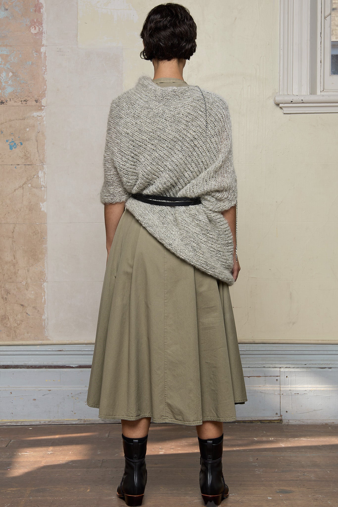 Back view of model wearing mohair cocoon belted, an asymmetric poncho in a white flecked colourway