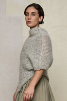 Side view of model wearing mohair cocoon, an asymmetric poncho in a white flecked colourway