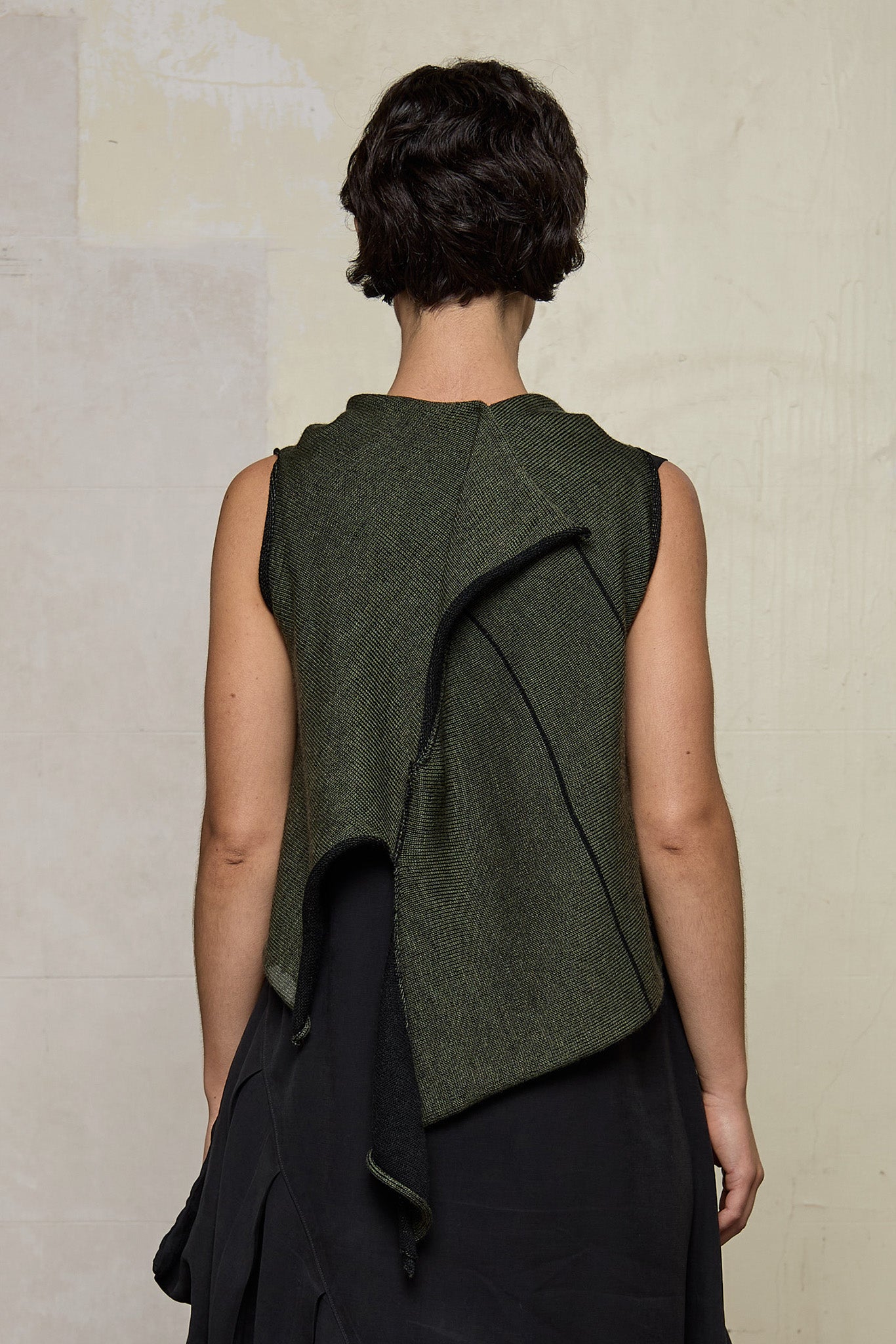 Model wears knitted asymmetric vest back to front, in army on black colour way. Designed and knitted in Melbourne by Wendy Voon knits