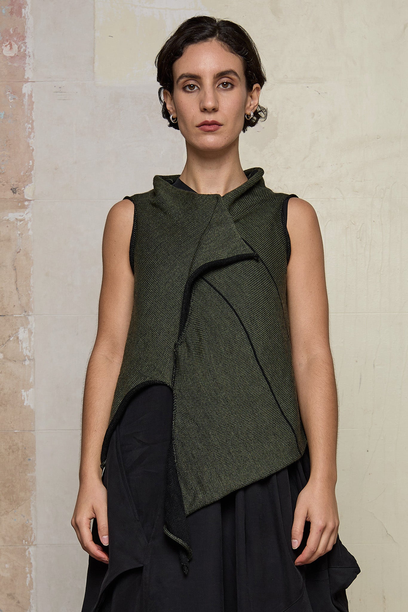 Model wears knitted asymmetric self-curling vest, in army green on black colourway. Designed and knitted in Melbourne by Wendy Voon knits.