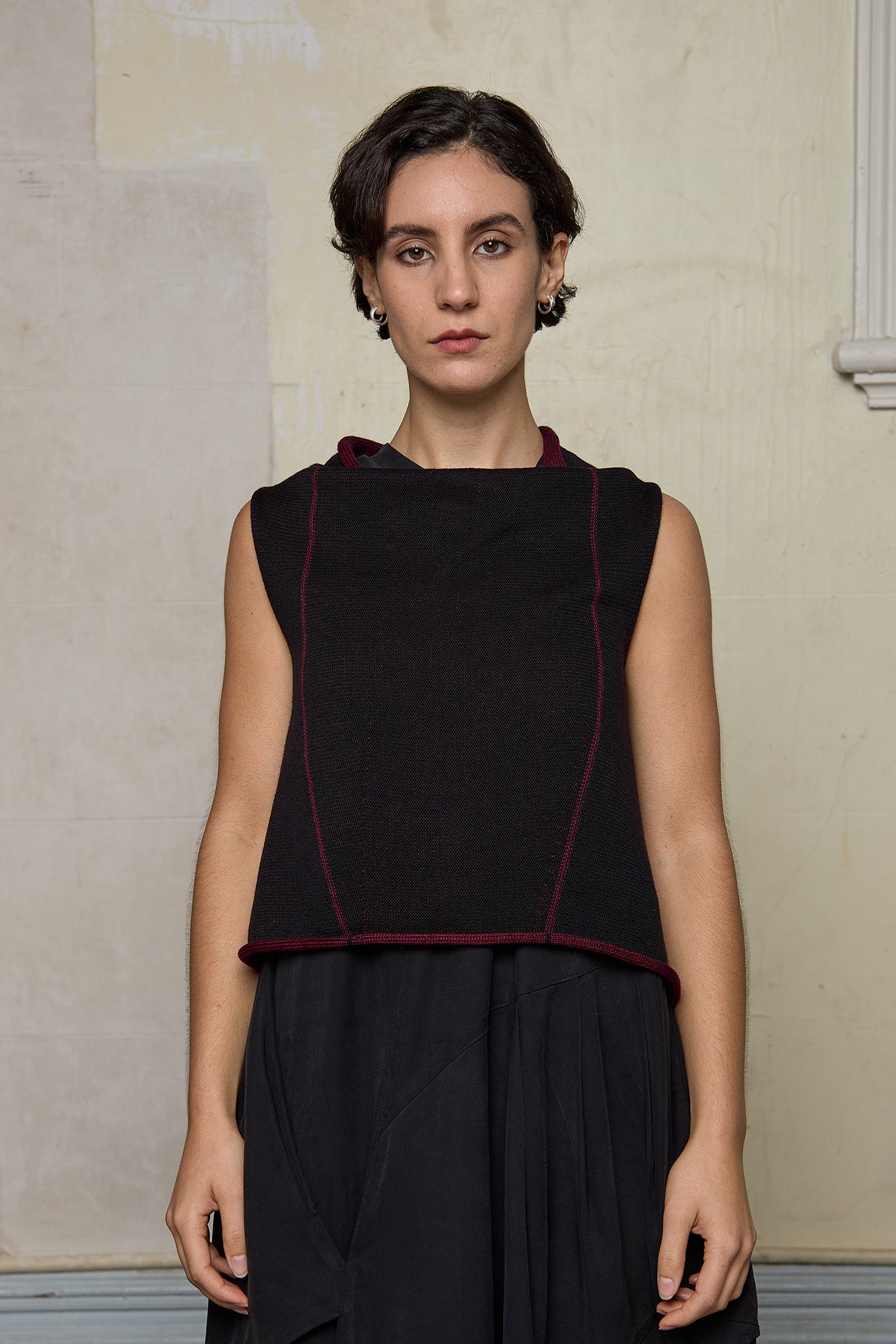 Model wears knitted asymmetric self-curling vest inside out, in burgundy on black colourway. Designed and knitted in Melbourne by Wendy Voon knits