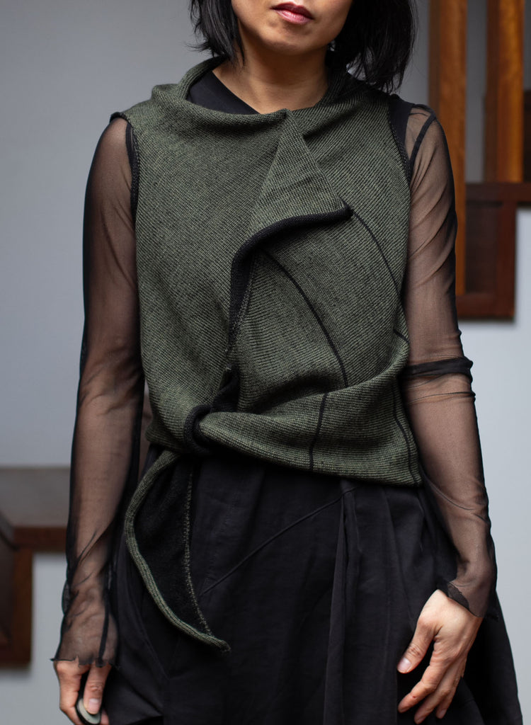 Model wears an asymmetric self-curling vest tied at the waist.  Vest is knitted in superfine merino wool,in an army backed with black colourway, designed and knitted in Melbourne by Wendy Voon knits.