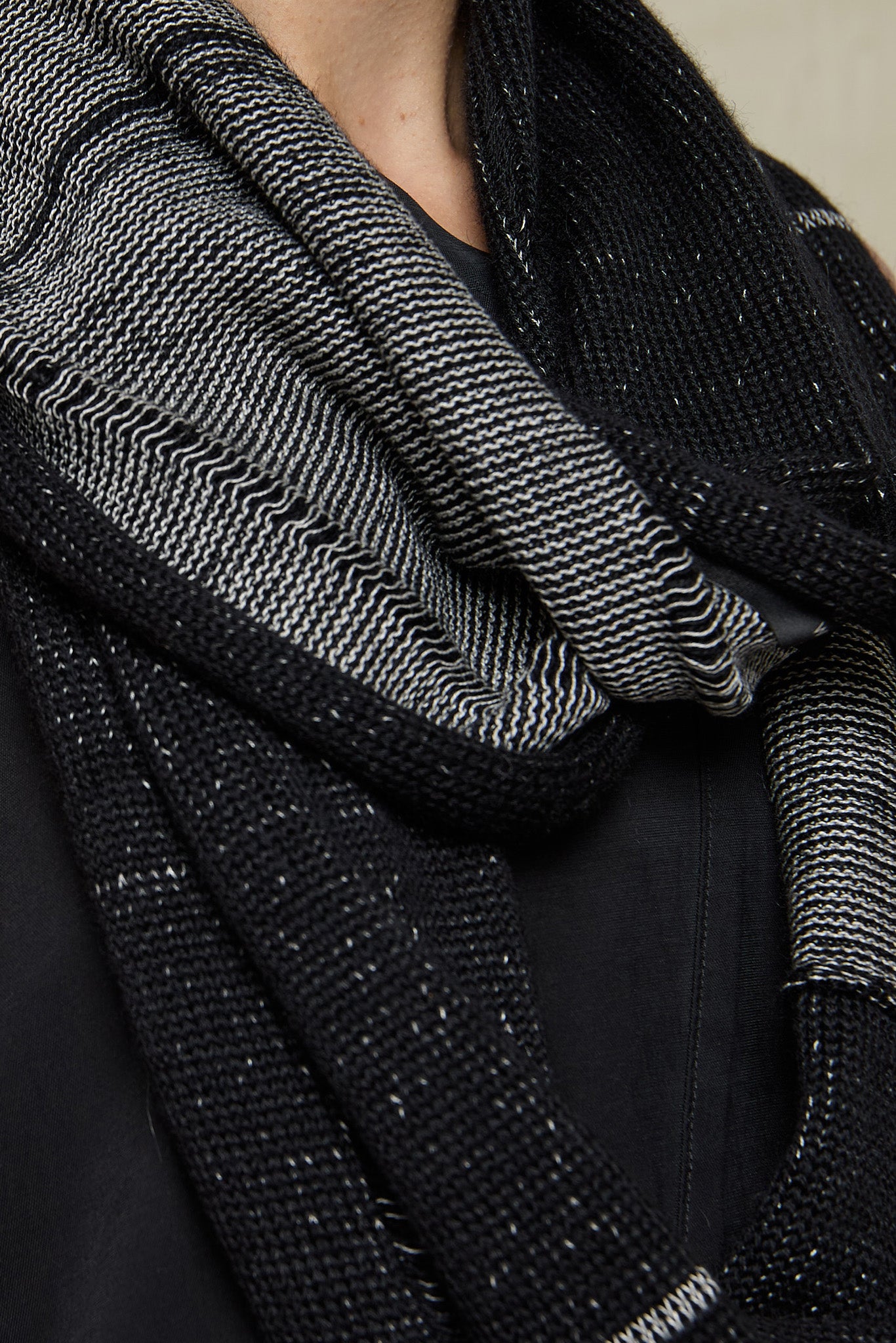 Close up fabric view of black and white infinity scarf, made from alpaca, merino wool and cotton