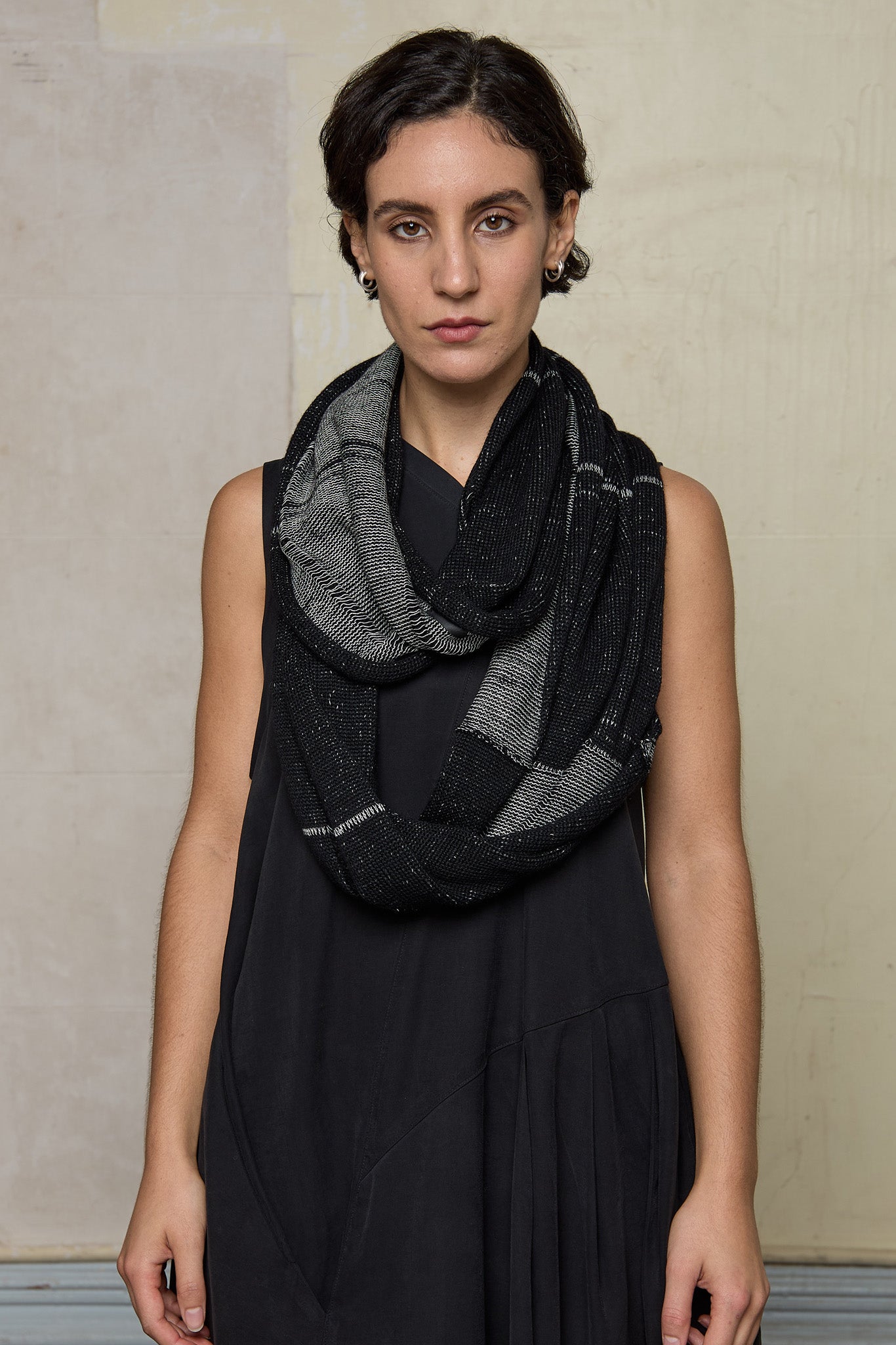Model wears knitted black and white infinity scarf, made from alpaca, merino wool and cotton