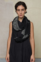 Model wears knitted black and white infinity scarf, made from alpaca, merino wool and cotton