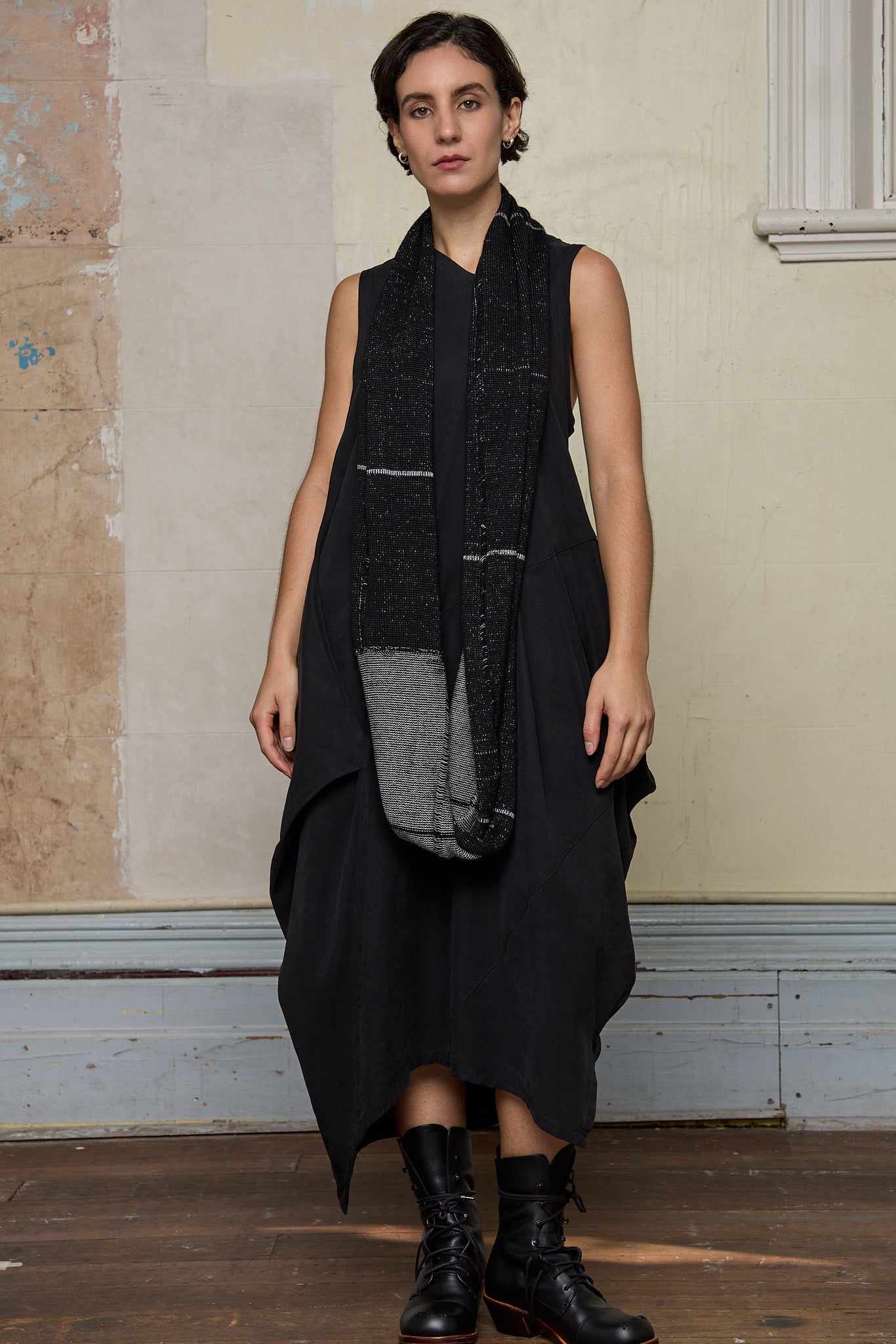 Model wears knitted black and white infinity scarf, made from alpaca, merino wool and cotton