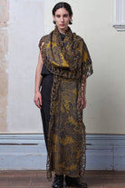 Model wears knitted damask scarf in a grey and gold colourway.
