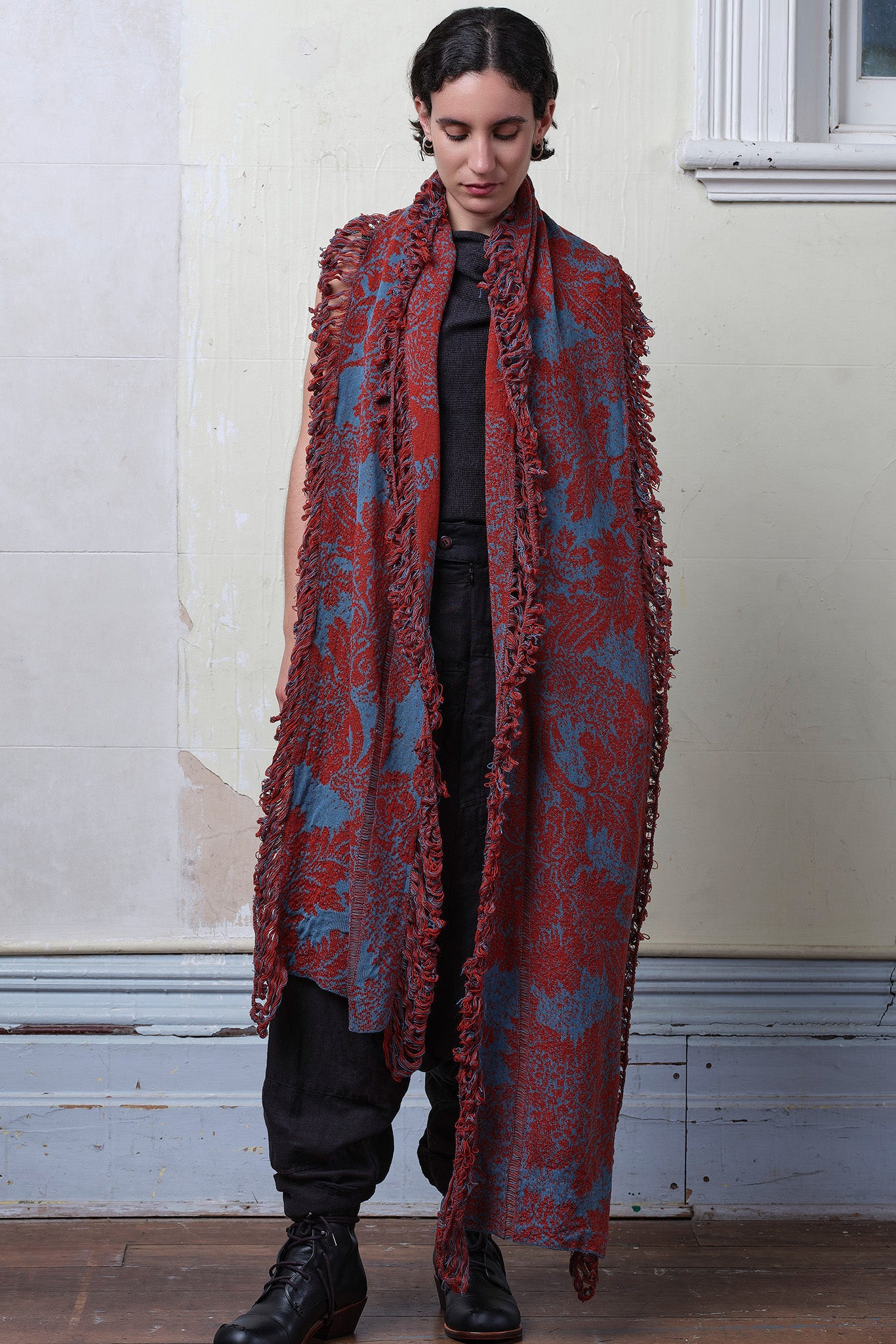 Model wears knitted wool/linen/cotton damask scarf in rust and lagoon blue colourway.