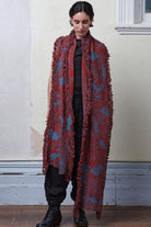 Model wears knitted wool/linen/cotton damask scarf in rust and lagoon blue colourway.