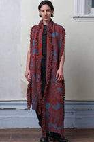 Model wears knitted wool/linen/cotton damask scarf in rust and lagoon blue colourway.