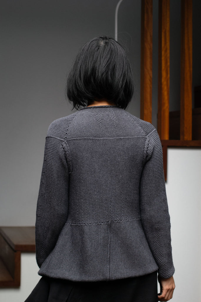 Back view of model wearing a knitted steel grey peplum riding coat, made from a chunky superfine merino yarn. This piece is designed and made in Melbourne by Wendy Voon knits. 